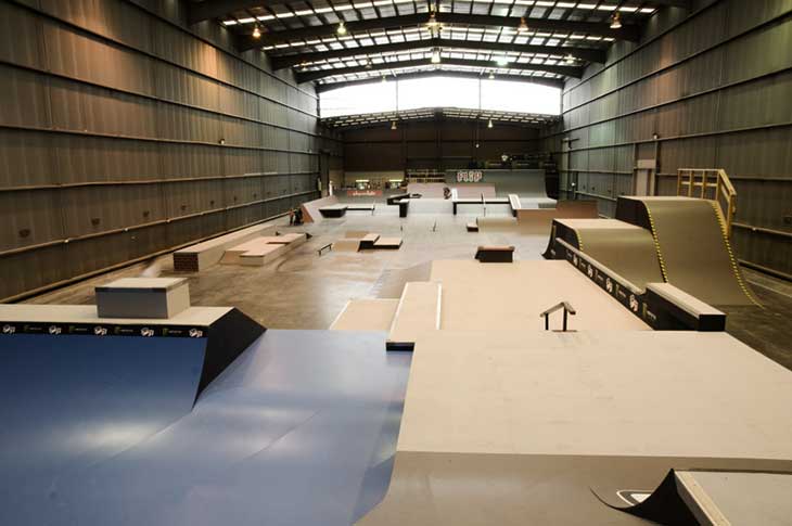 Large indoor skatepark with timber ramps, ledges and a quarter pipe inside a warehouse