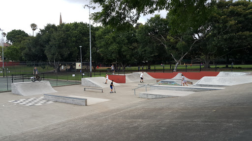 Concrete skate plaza with ledges, banks and red features in a Sydney park